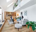 wooden floor, high ceiling, two wooden shelves, wooden table, sofa, chair, potted plants, picture frames
