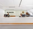 white desk, 2 computer screens, people, logo 'SPACES.'