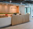 Modern and open office space with wooden reception desk, grass decor, and signage for 'Spaces'
