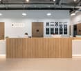 Reception desk, wooden doors, monitors, plants, ceiling lights, wall-mounted frames