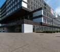 modern office building, black and white exterior, large windows, multiple floors, parking area in front