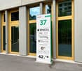office building with glass doors, grey and yellow columns, sign with address and company names