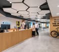 Reception desk, standing bicycle, decorative wall, large hex ceiling tiles, open office layout, standing people