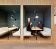 Cushioned booth seating, desks, lamps, wooden floor