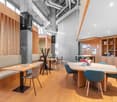 Modern office with wooden flooring, wooden furniture, and tables and chairs for seating.