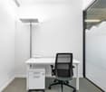 white desk, black office chair, white drawers, white walls, glass wall with pattern