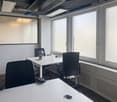 modern office room with white walls, white desks, black chairs, large windows, ceiling lamps