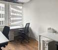 modern office with white walls, wooden floor, large windows, office chairs, desks, small plant