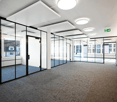 modern office space with glass walls, carpeted floor, large windows, exit sign