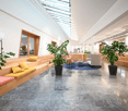 modern office with wooden benches, plants, marble flooring, skylights