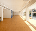 Open space, wooden flooring, white walls, large windows with views of the street