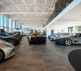 spacious showroom with large windows, multiple high-end sports cars, modern lighting, and polished flooring