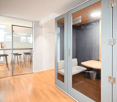 Office phone booth with glass walls, a small desk, and a bench.