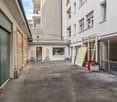 Empty parking lot, concrete floor, green doors, white walls, windows, potted plants, trash bin