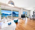 modern open floor plan, large windows with balcony, wooden floor, table, sofa, TV, plants