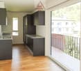 Modern kitchen with dark cabinets, granite countertops, and large windows overlooking a balcony or terrace.
