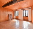 Spacious room with wooden walls and ceiling, hardwood floor, large windows, and a fireplace