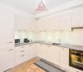 White cabinets, marble countertops, oven, microwave, sink, grey floor mat, light tiled flooring