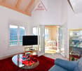 large glass windows, red carpet, modern style, flatscreen TV, glass table, sofa, glass door with balcony