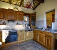 modern kitchen with wooden cabinets, granite countertops, oven, dishwasher, sink, and tiled flooring