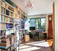 Filled bookshelves, computer desk, chair, clock, carpet, rug
