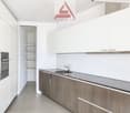 Modern kitchen with granite countertops, stainless steel sink, wooden cabinets, integrated oven, under cabinet lighting, dishwasher, and washing machine