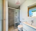 white tiles, glass shower enclosure, white toilet, white sink, wooden framed window