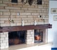 Brick fireplace with a wooden mantel, two candles, a chandelier, a copper pot, and a wooden shelf