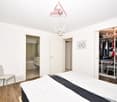 large bed, white and black sheets, chair, mirror, closet with many clothes, chandelier, picture