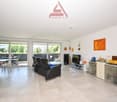 modern living room with couch, desk, TV, cabinets, painting on the wall, windows