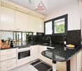 Modern kitchen, white cabinets, black granite countertops, gas stove, integrated dishwasher, island bar, window