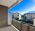 Balcony with metal railing, view of nearby buildings and mountains in the distance