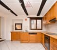 The kitchen has tiled floor and wall, wooden cabinets, sink with faucet, a dishwasher, and an oven.
