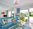 living room with blue sofa, glass table, modern decor, glass doors leading to terrace, lamps, painting