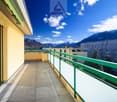 terraced apartment balcony, green railings, clear skies, mountain range in the background