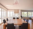 wooden dining table, 6 chairs, large windows, beige couch, wooden floor