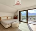 large bed, white bedding, 2 nightstands, lamp, wooden cabinet, sliding glass door, balcony, view of mountains
