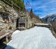 Stone wall, fireplace, wooden bench, snow, mountains in the background