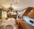 Dining room with a table, chairs, fireplace, kitchen, and a staircase