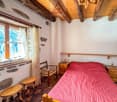 bedroom with wooden bed, wooden chair, wooden stools, wooden nightstands, window with curtains, wooden ceiling