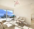modern living room with large windows, balcony, desk, chairs, couch, rug, lamps