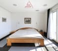 wooden bed, white bedding, wooden nightstands, lamps, framed pictures, sliding glass door, balcony, rug