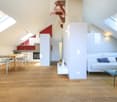 open space with wooden floor, white couch, dining table, kitchen, skylights