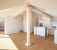 modern kitchen with white cabinets, wooden floor, central column, chandeliers, microwave, sink, faucet