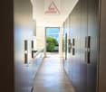 long hallway with wooden floor, modern cabinets, open door to balcony