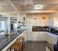 modern kitchen with granite countertops, white cabinets, wooden beams, large windows, bar stools, various kitchen appliances
