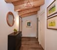 wooden ceiling, wooden floor, white walls, round mirror, wooden cabinet, two framed paintings
