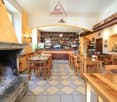 wooden tables and chairs, fireplace, wooden bar counter, shelves with bottles, checkered floor