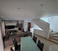 modern living room, fireplace, large windows, dining table, couch, television, shelves, stairs