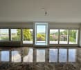 Spacious living room with large windows offering a scenic view of the surrounding landscape, including trees and flowers. The room has a marble floor with a reflective surface, creating a luxurious and elegant atmosphere.